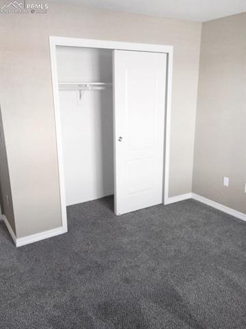 Unfurnished bedroom featuring a closet and dark colored carpet