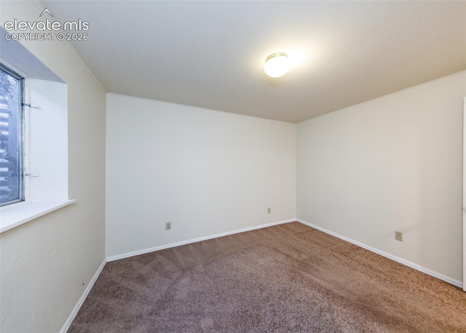 Room featuring neutral wall tones, carpeted flooring, a recessed window, and a flush-mount ceiling light fixture