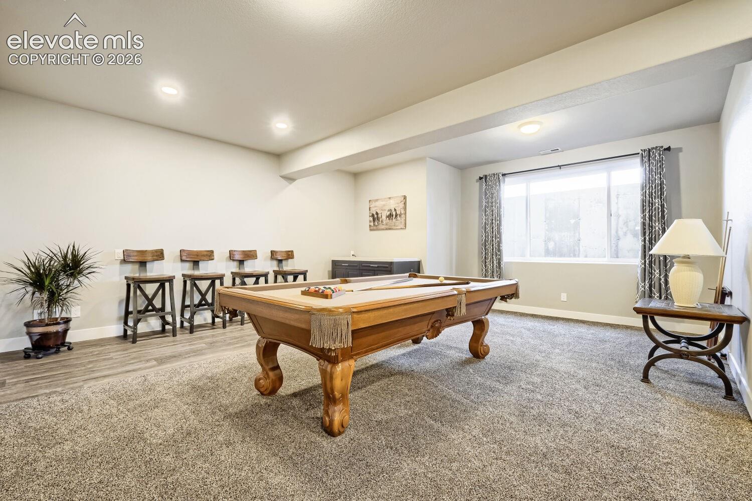 Recessed ceiling lighting, a large window with privacy coverings, and carpet flooring