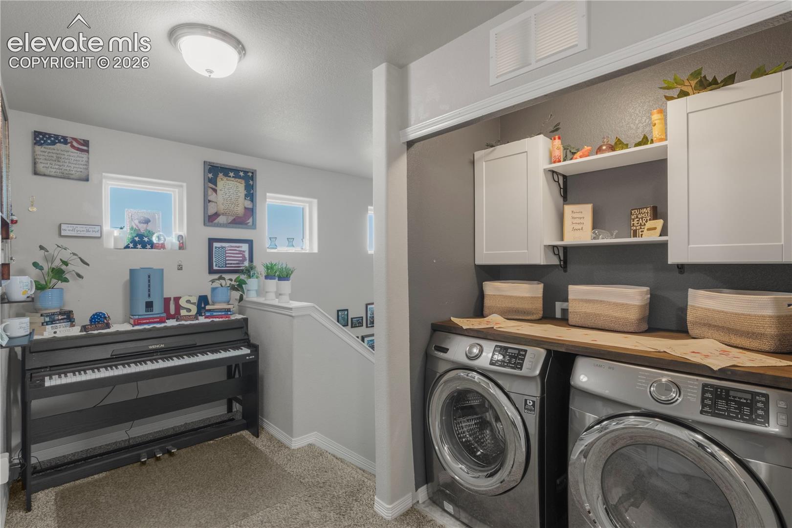 Dedicated laundry area featuring white cabinetry, an integrated shelf, and a wood-finish countertop
