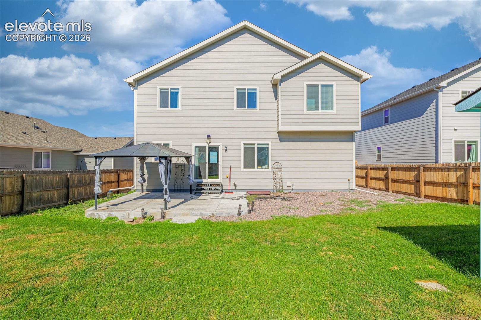 Expansive backyard with a manicured lawn, concrete patio, and privacy fencing