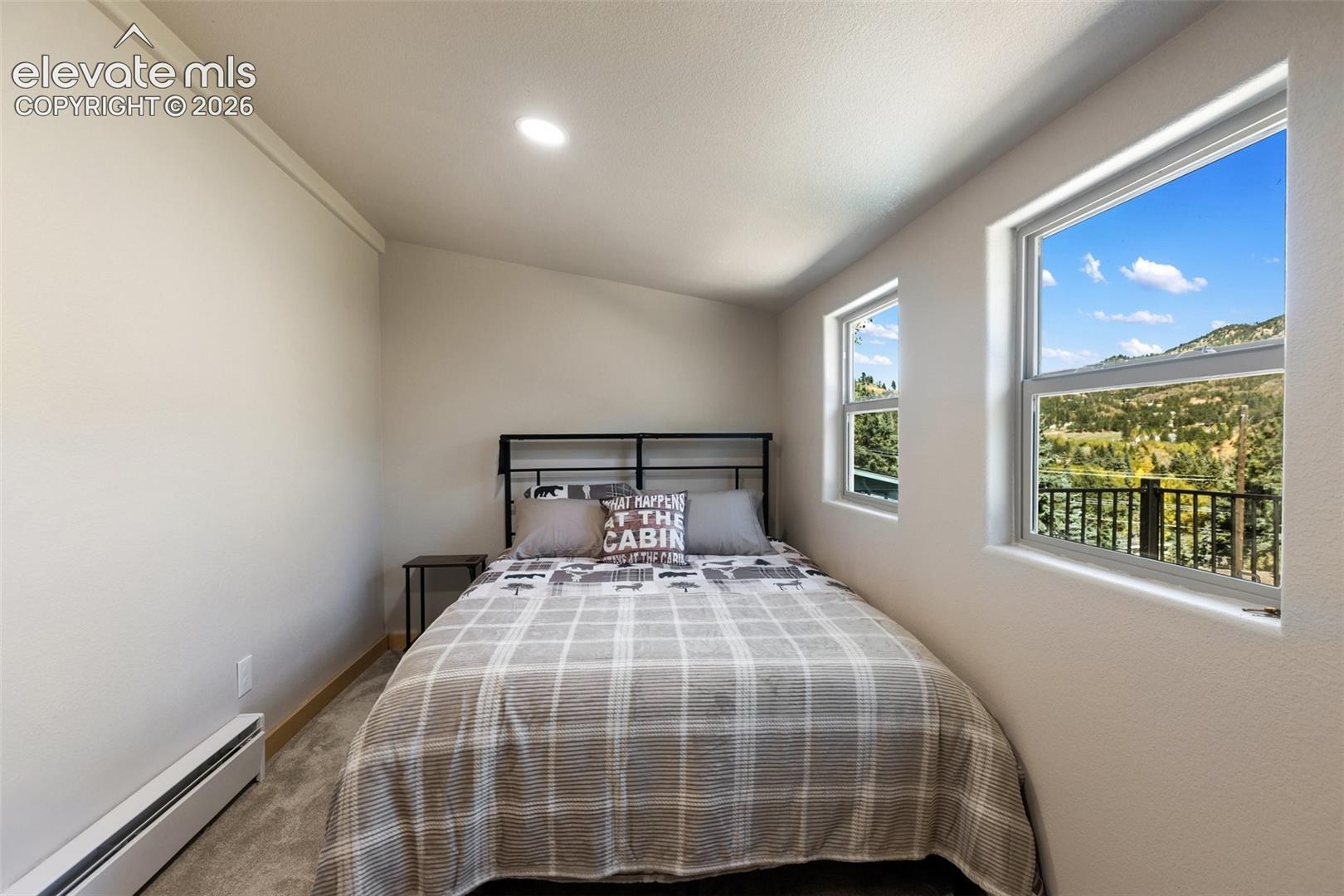 Neutral-toned interior space featuring wall-to-wall carpeting, recessed ceiling lighting, and windows showcasing mountain and landscape scenery
