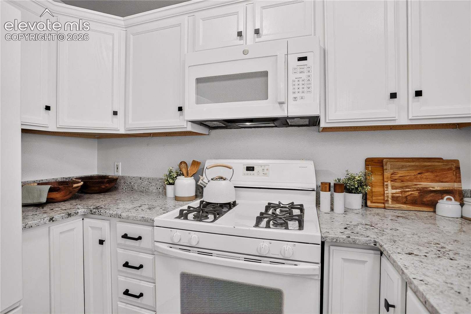 Kitchen has granite countertops and a four burner gas range.