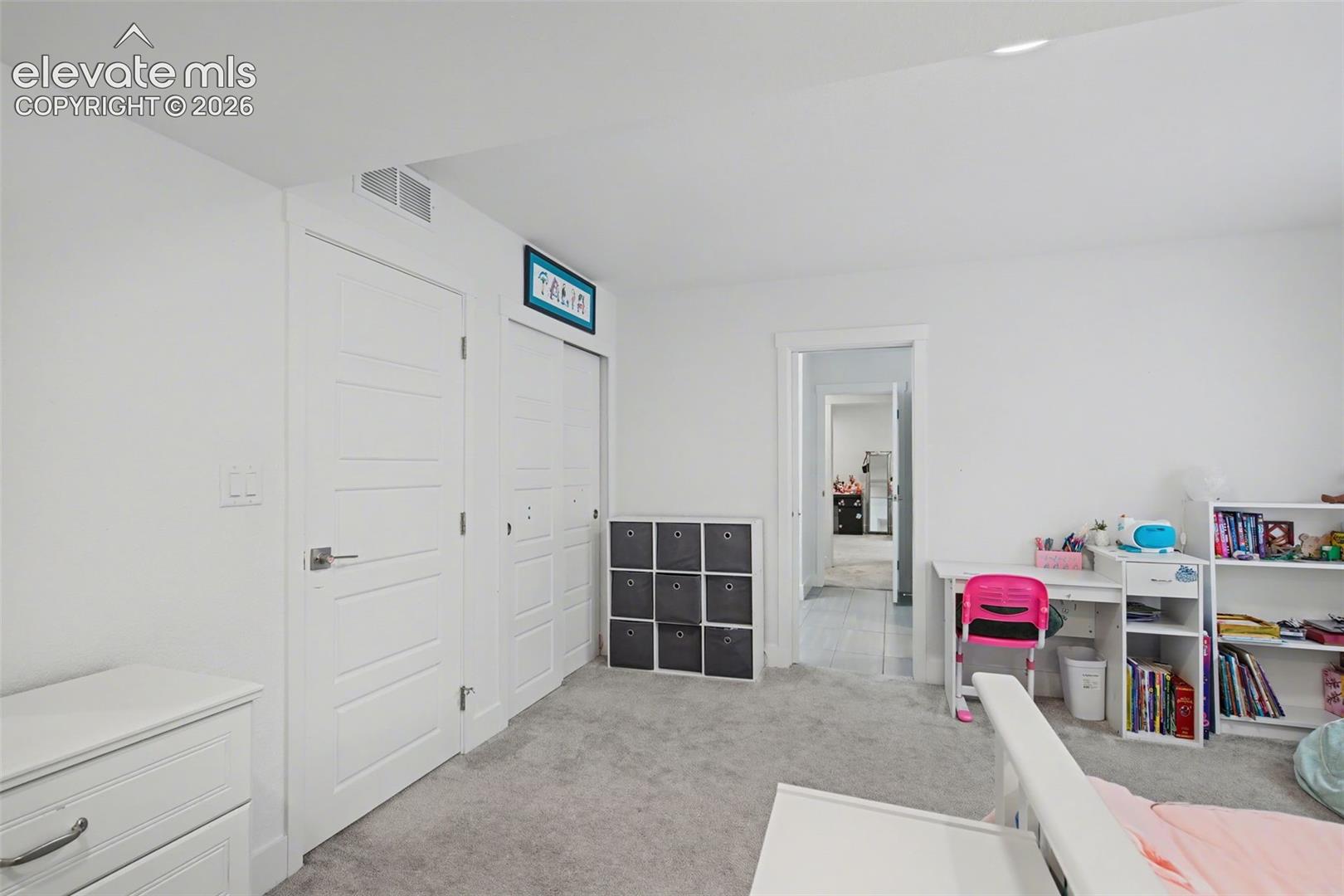 Bedroom with light colored carpet and a closet