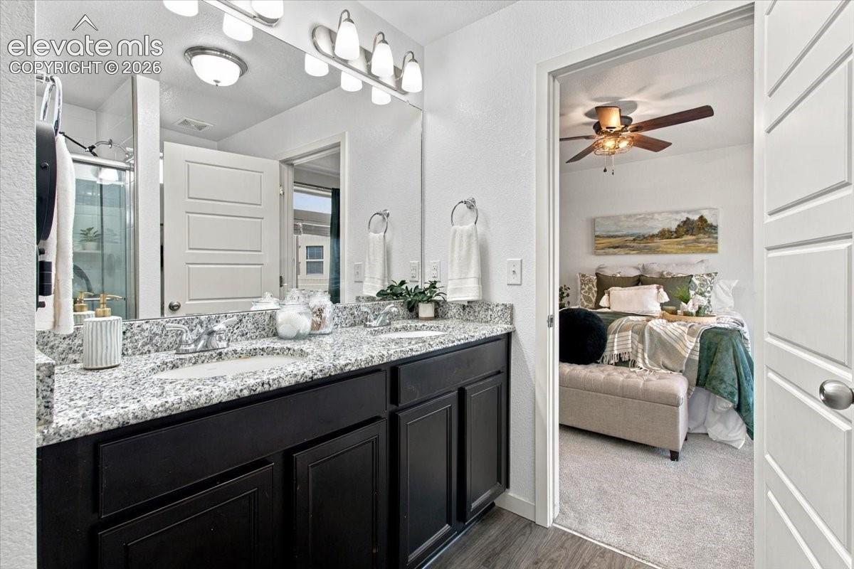 Dual vanity with granite-style countertop, dark wood-finish cabinetry, and contemporary light fixtures
