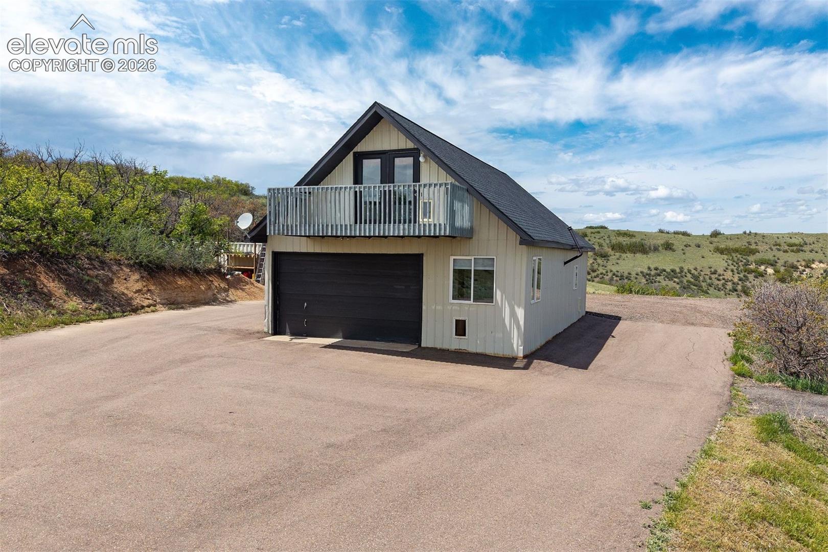 Detached barn with ADU apartment above — two-car overhead door on lower level and private deck with south-facing views on upper level.