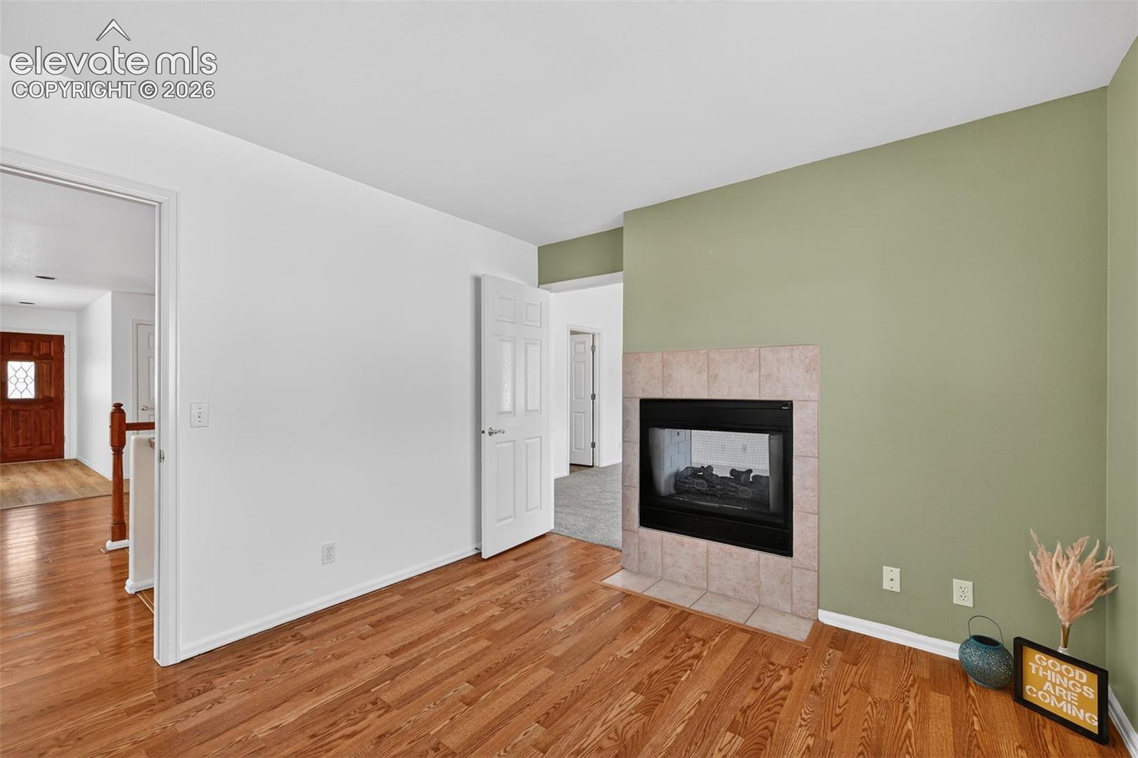 Wood-finish flooring, fireplace with a tiled hearth and surround, and six-panel interior doors