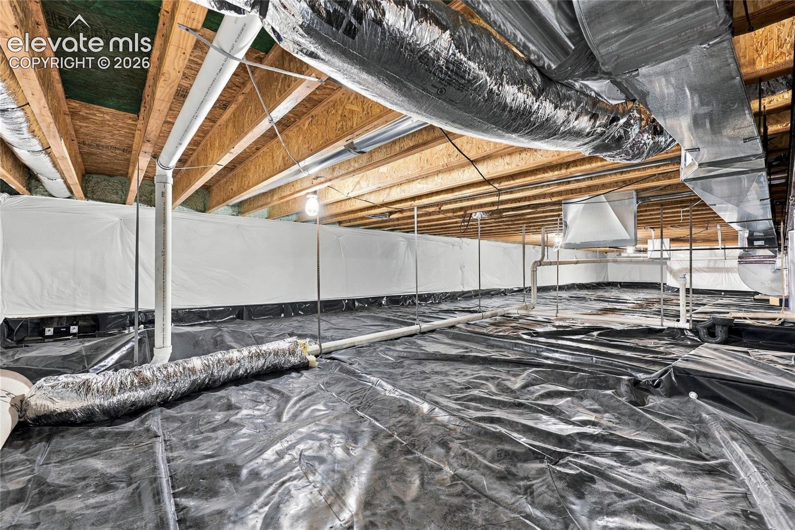 Crawl space featuring a vapor barrier, exposed joists, insulation, and metal HVAC ducting