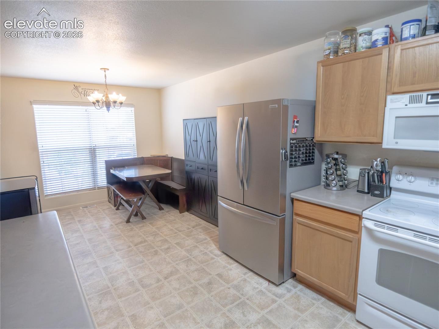 Eat-in kitchen featuring light wood cabinetry, light-toned countertop, and tile-finish flooring