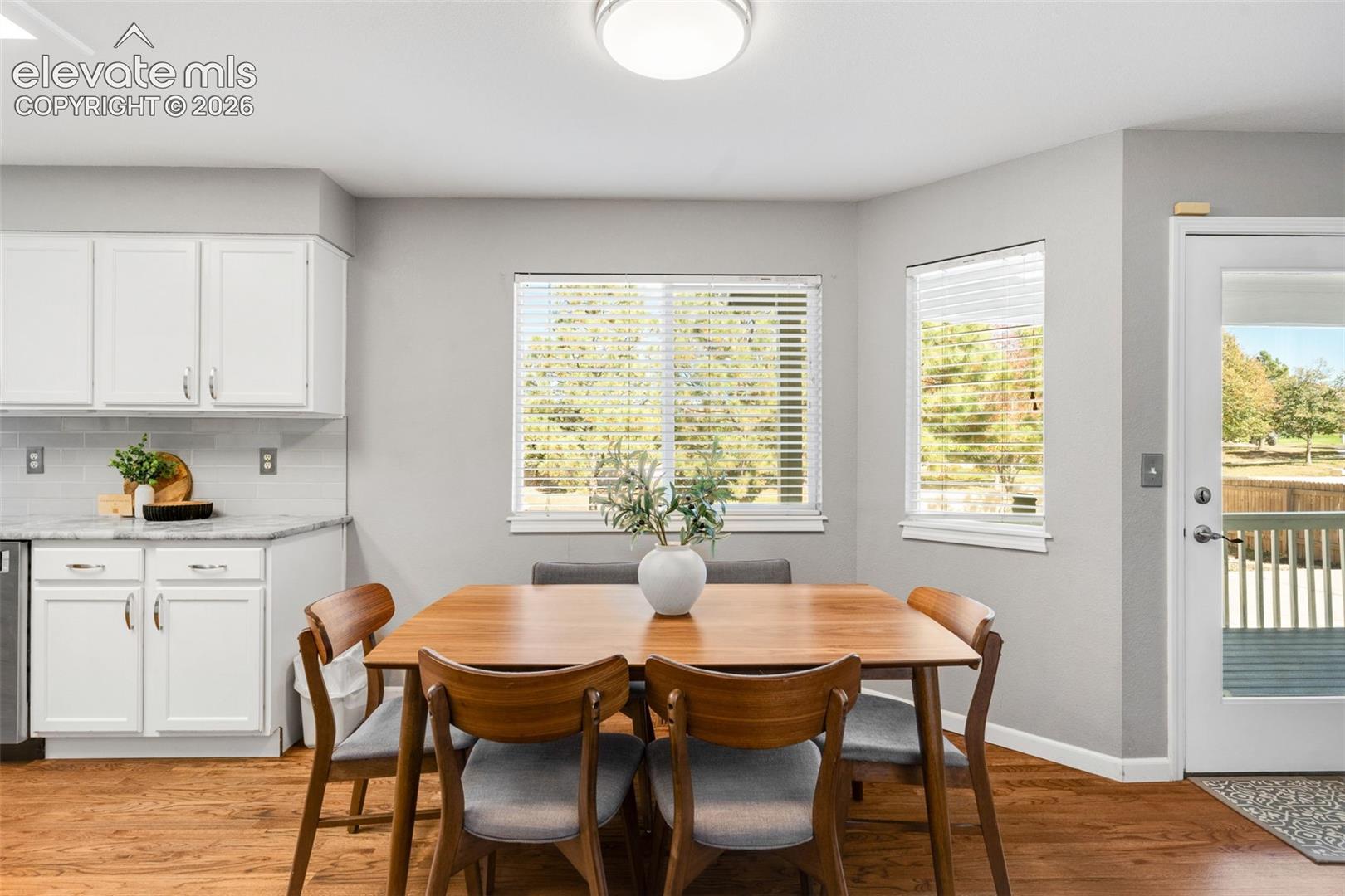 Kitchen area featuring white shaker-style cabinetry, stone-finish countertops, wood-finish flooring, recessed lighting, and a glass-paneled exterior door