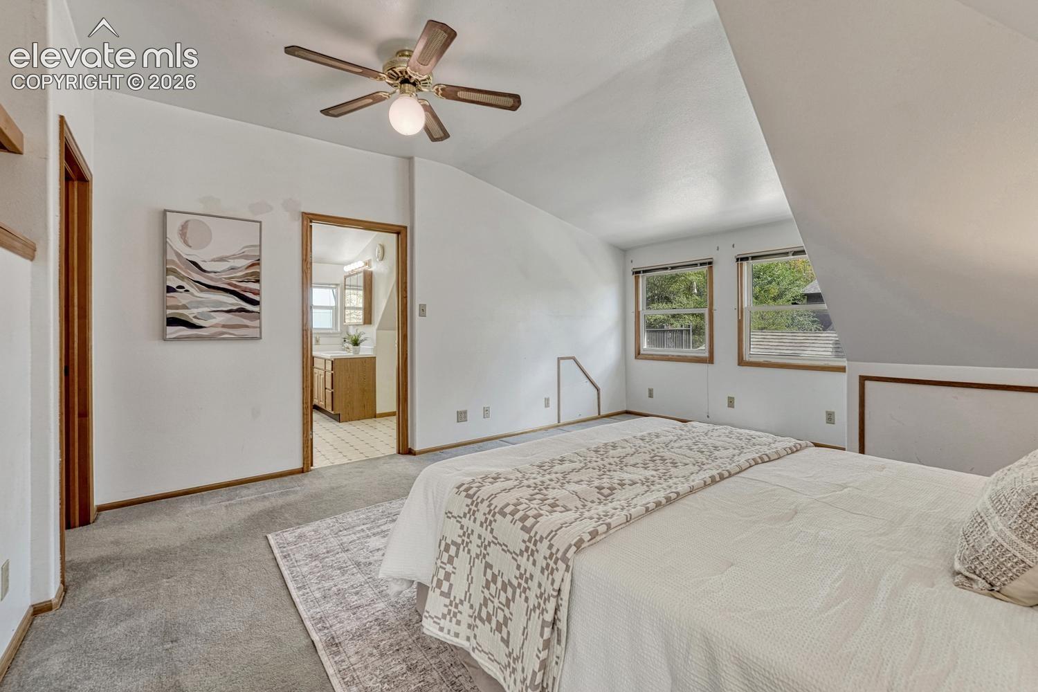 Carpeted room with a ceiling fan, two windows, and wood-finish trim