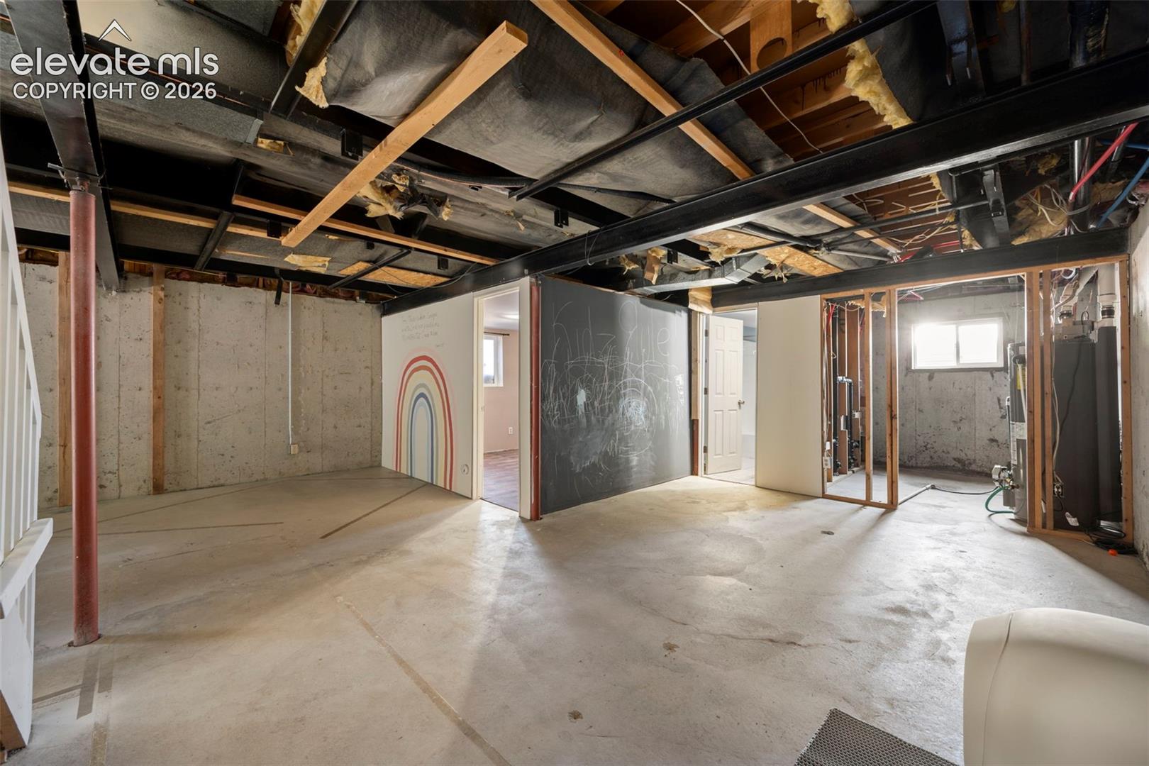 Unfinished lower level featuring exposed ceiling joists, concrete flooring, steel support beams, and exposed wall framing