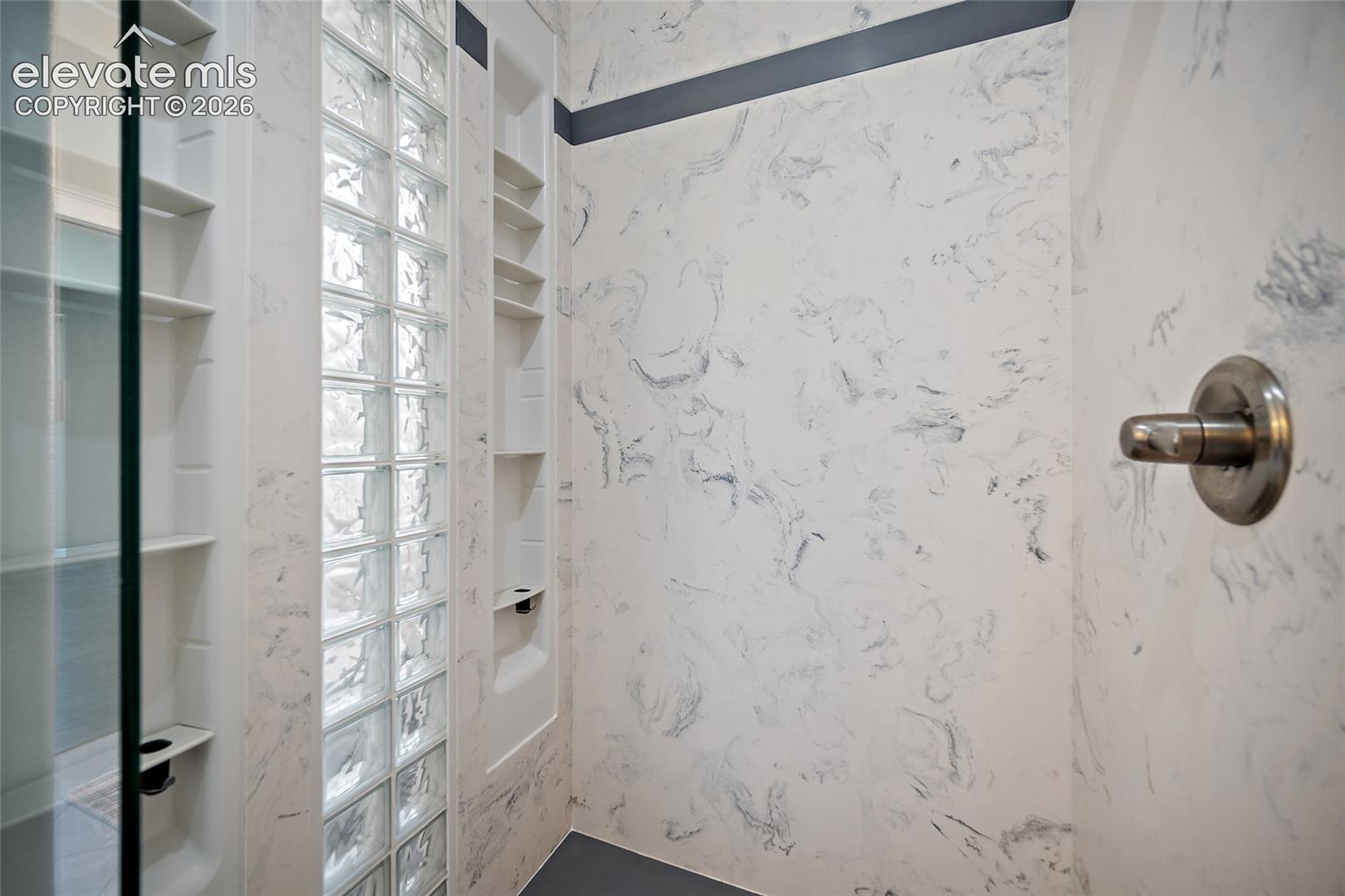 Custom shower with shelves and private glass that allows light to enter.