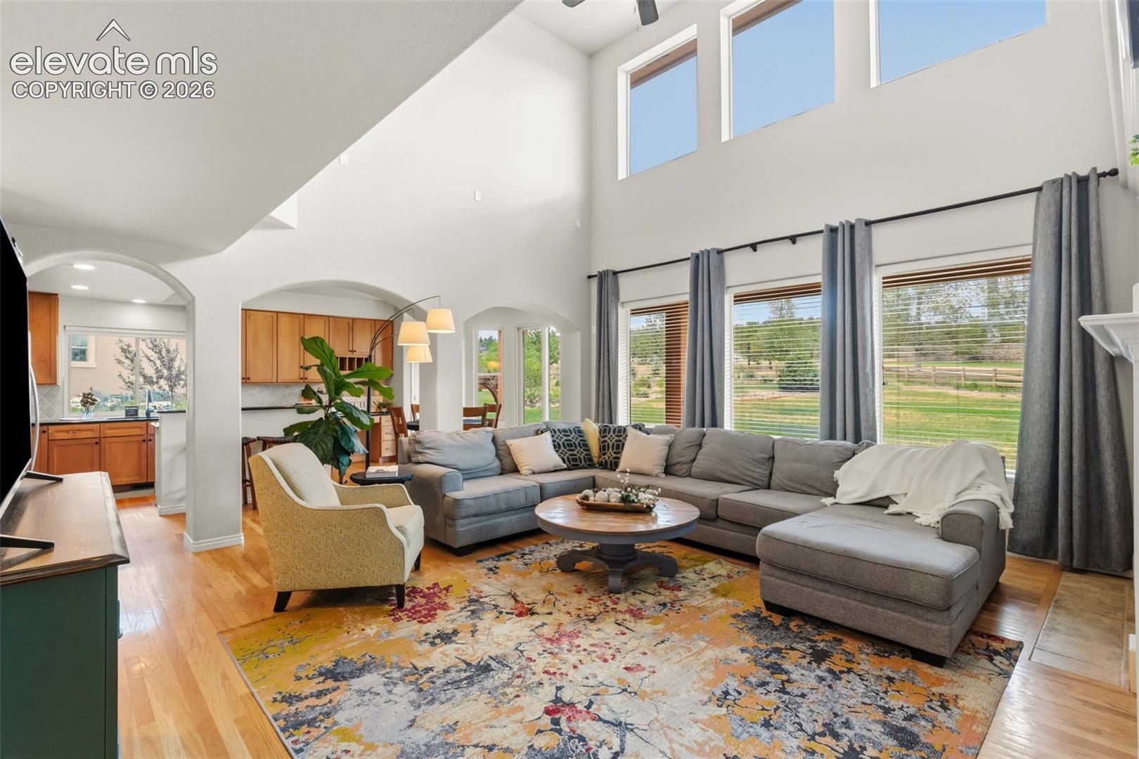 Spacious living area featuring high vaulted ceilings, multiple arched doorways, and wood-finish flooring, gas fireplace