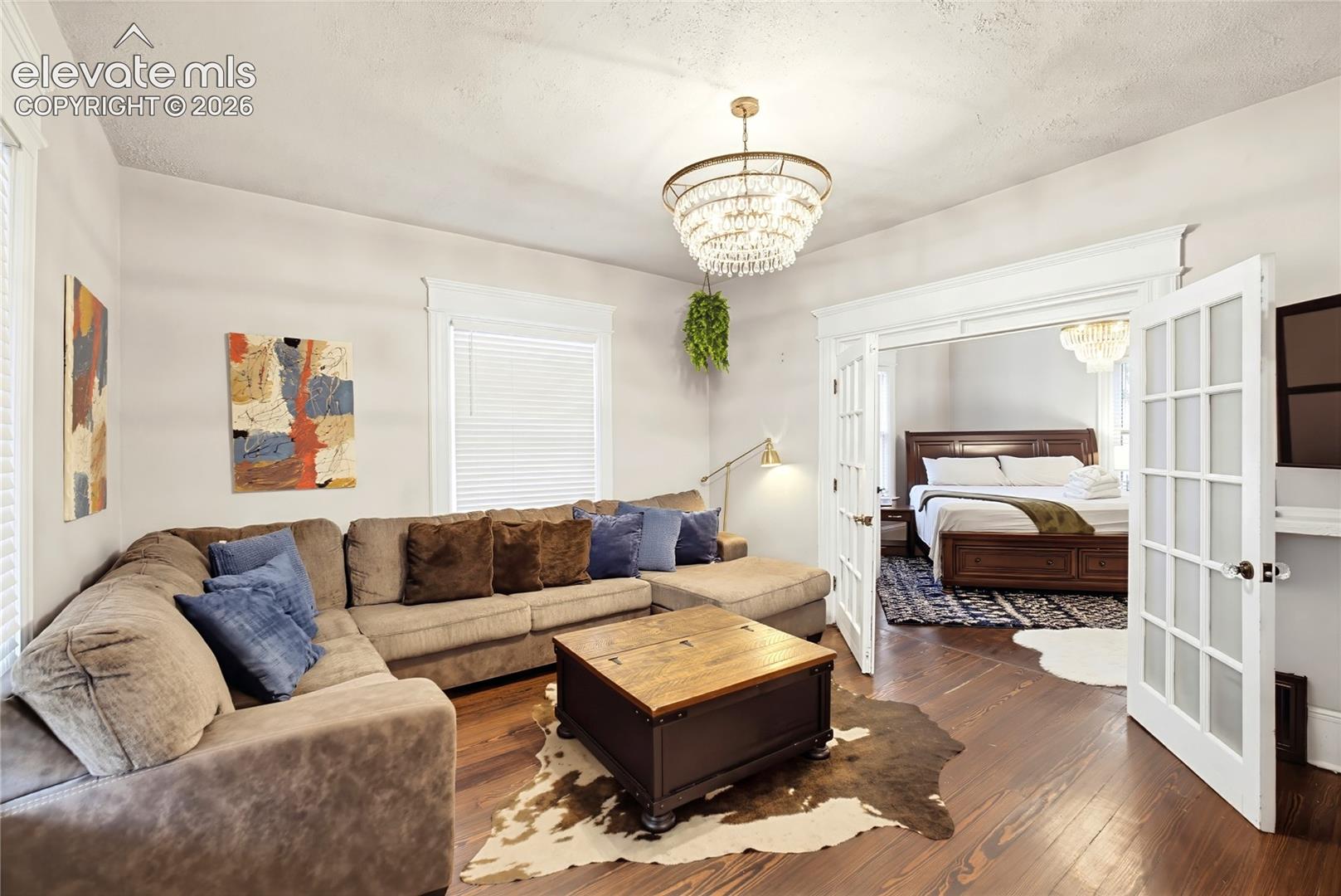 Hardwood flooring, decorative chandelier, white trim, recessed entry, and French doors
