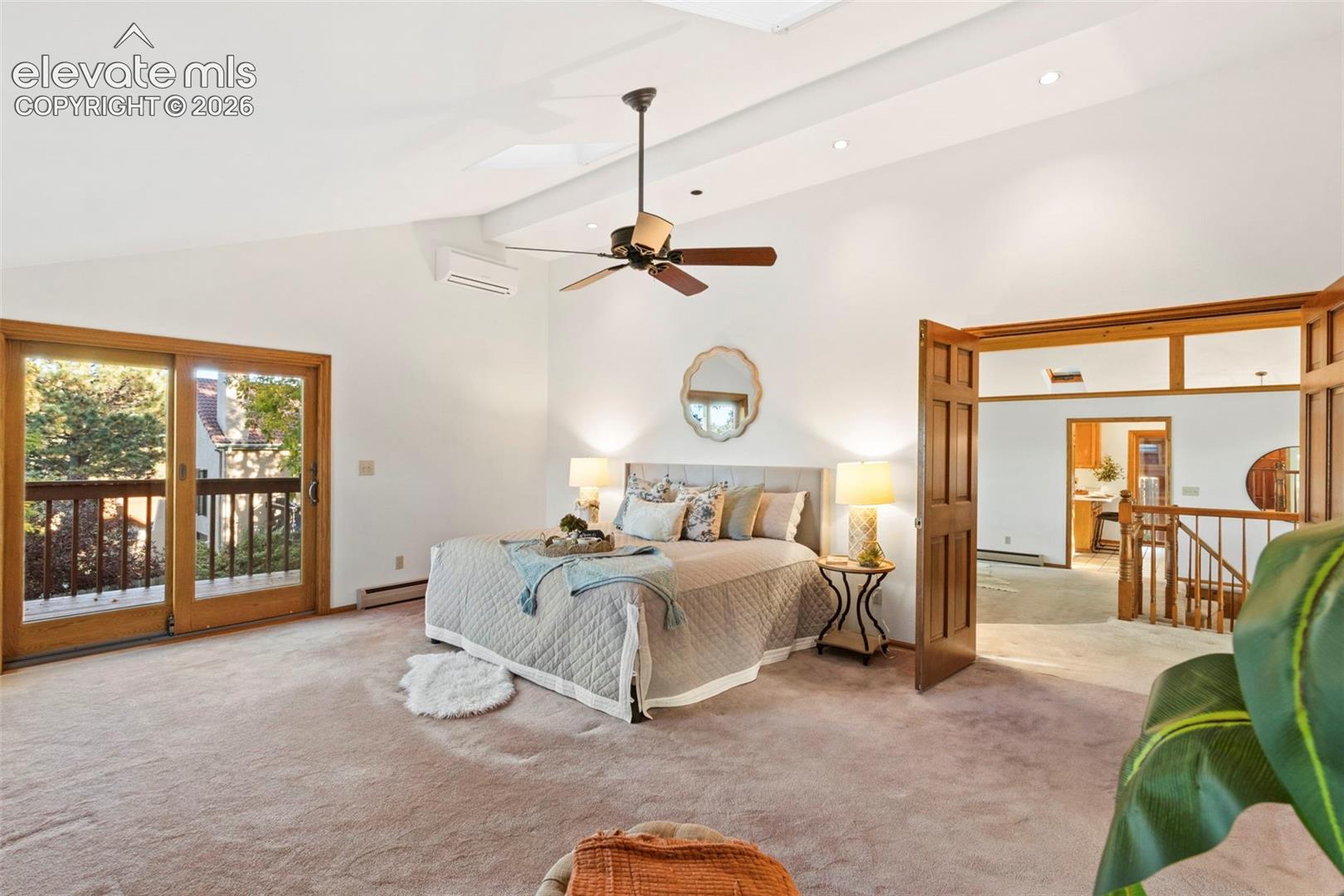 Vaulted ceiling with recessed lighting, central ceiling fan, sliding glass doors to a balcony, and double wooden swing doors