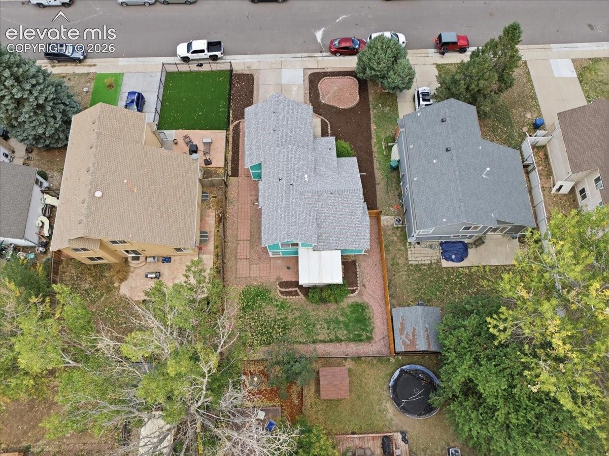 Aerial perspective of a multi-level home featuring a brick-paved patio, an attached covered deck, and a fenced backyard