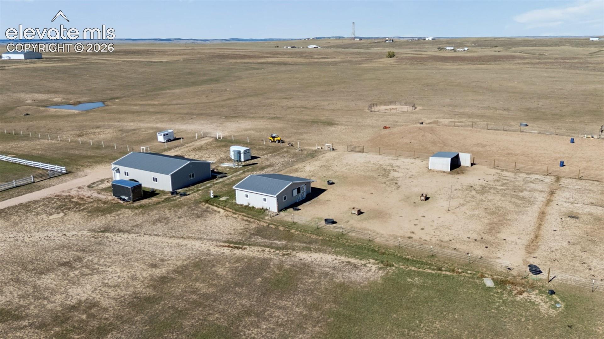 Expansive acreage featuring multiple metal-sided outbuildings, enclosed paddock areas, and peripheral perimeter fencing