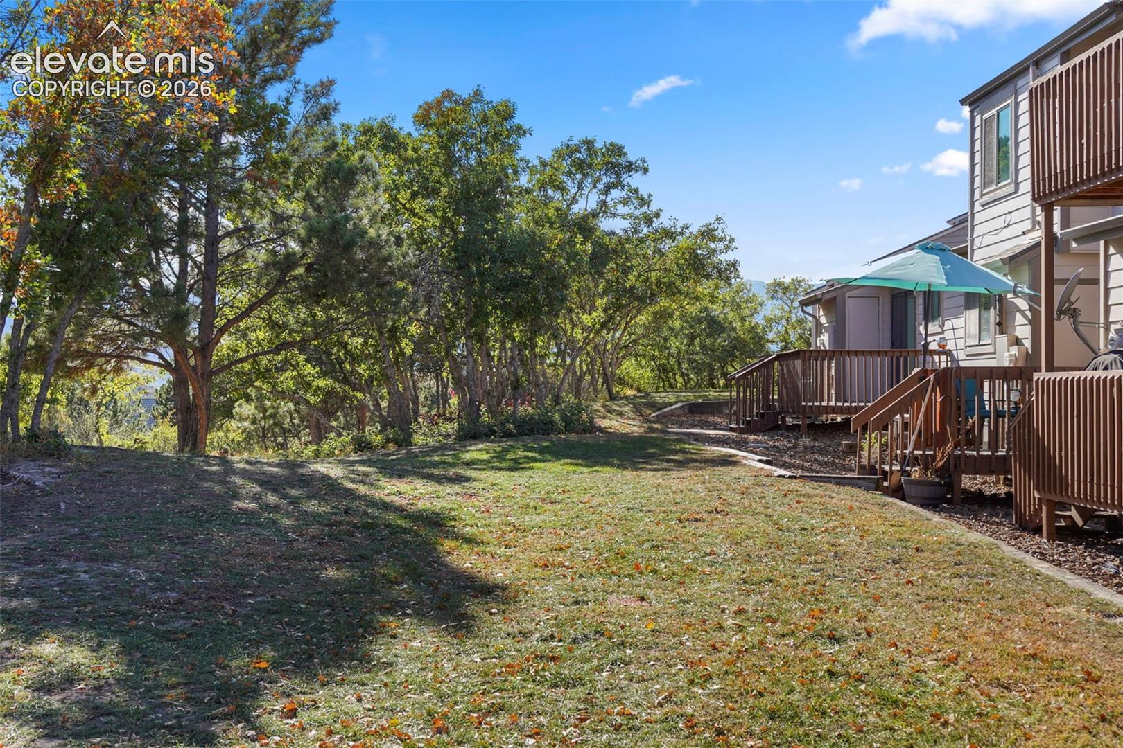 Expansive lawn area, mature trees, multi-level wood deck, and wood-sided exterior