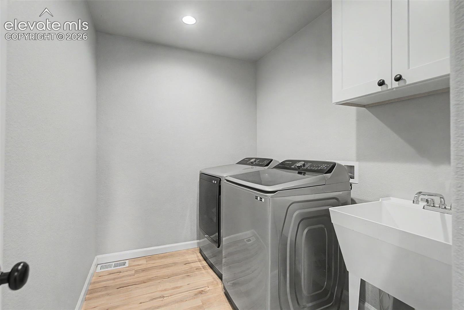 Dedicated utility area featuring wood-finish flooring, recessed lighting, a utility sink with chrome fixtures, and upper cabinetry for storage