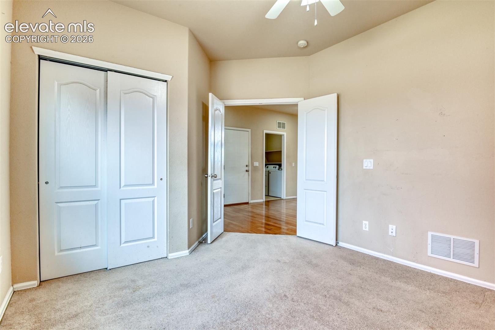 Room featuring vaulted ceilings, carpeted flooring, and white paneled doors, including a double-door closet