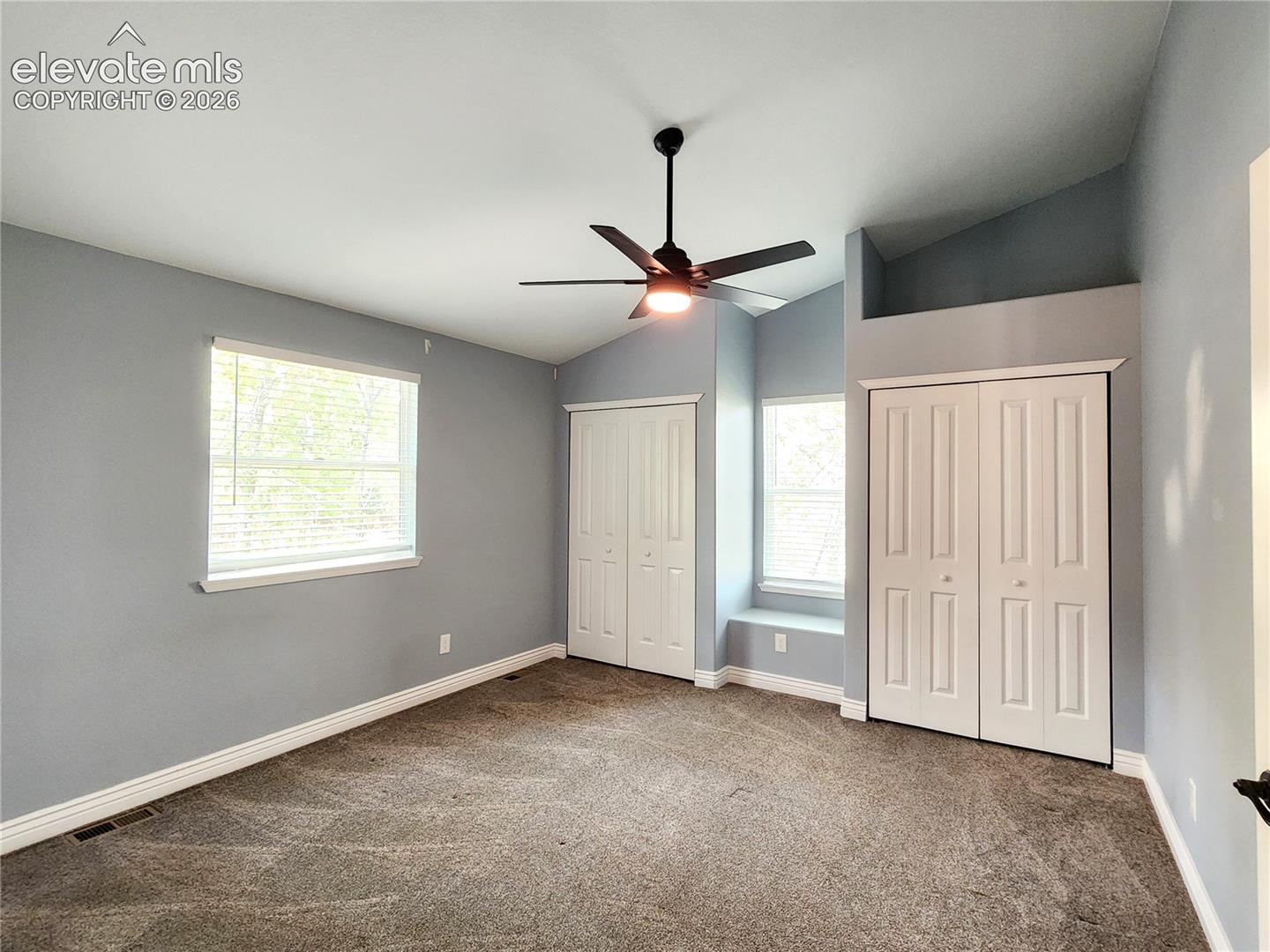 Generously sized primary suite featuring plush carpeting and a ceiling fan