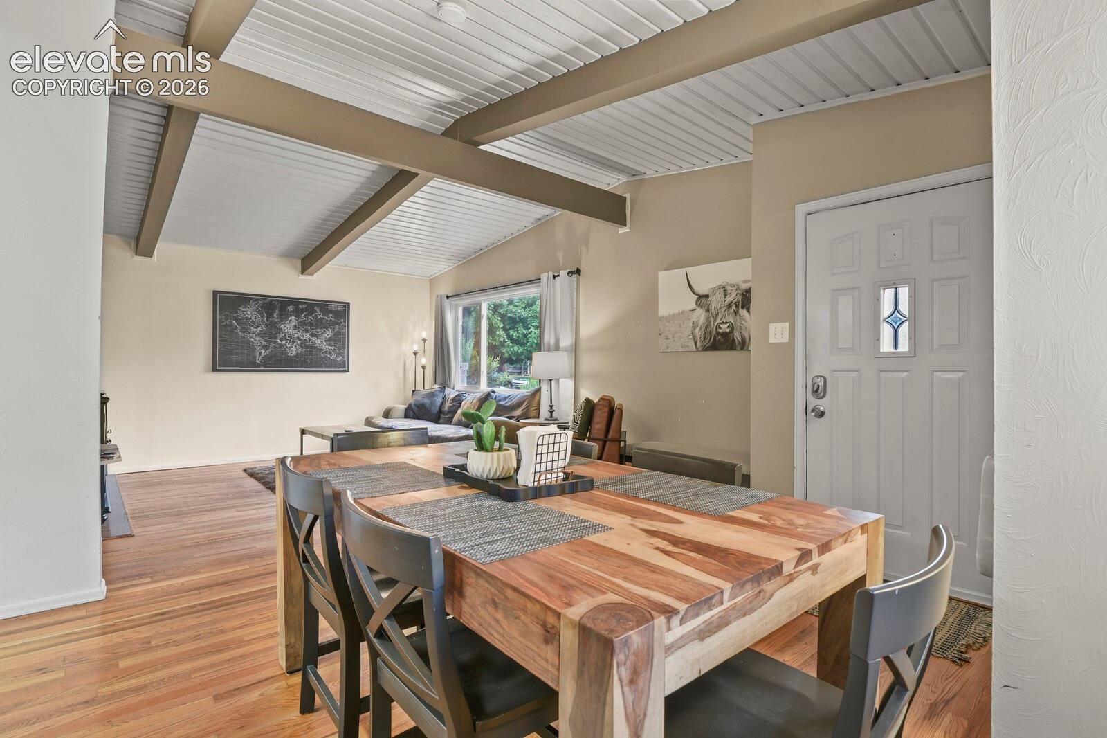 Dining area with view of tongue-in-groove ceiling, living room, and entrance.