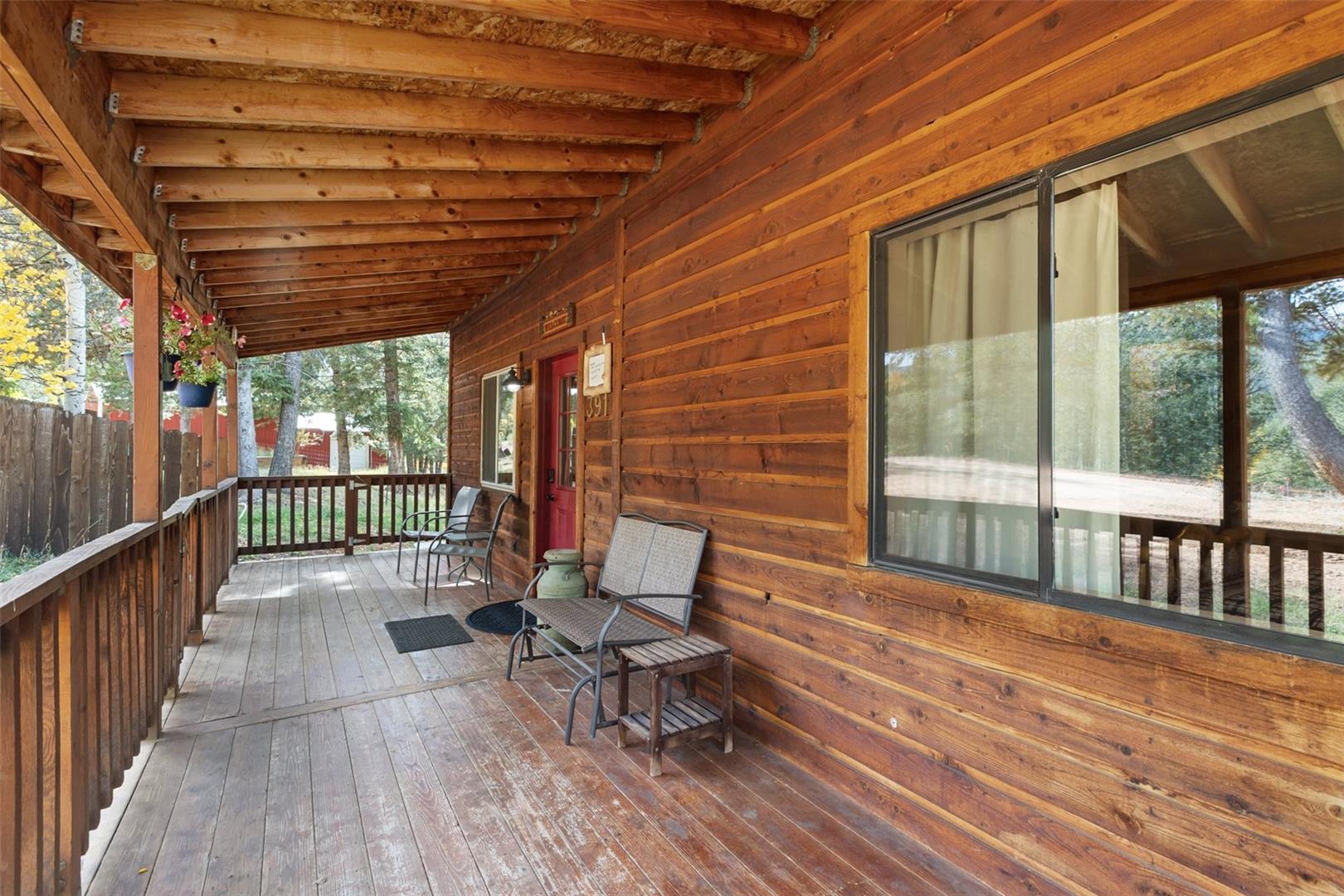 Expansive wood-plank porch with exposed beam ceiling, wood railing, and natural wood siding