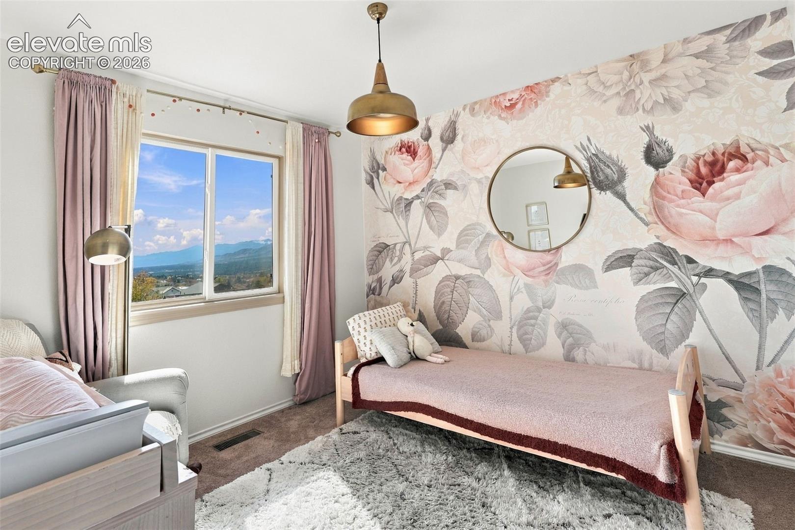 Room featuring floral wall covering, mountain scenery, carpeted flooring, and brass-finish pendant lighting