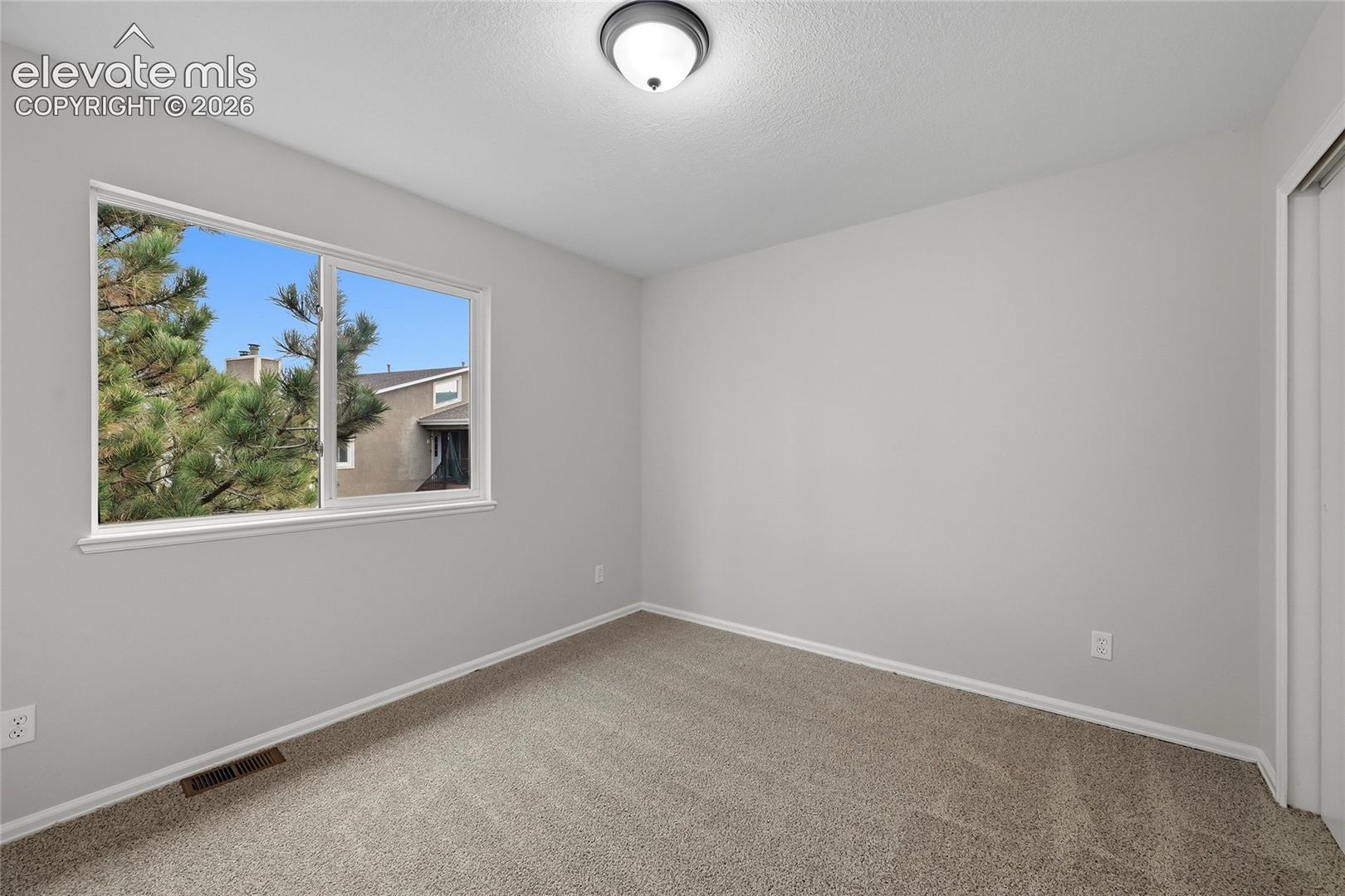 Neutral-toned walls, wall-to-wall carpeting, single-pane sliding window, and flush-mount ceiling lighting