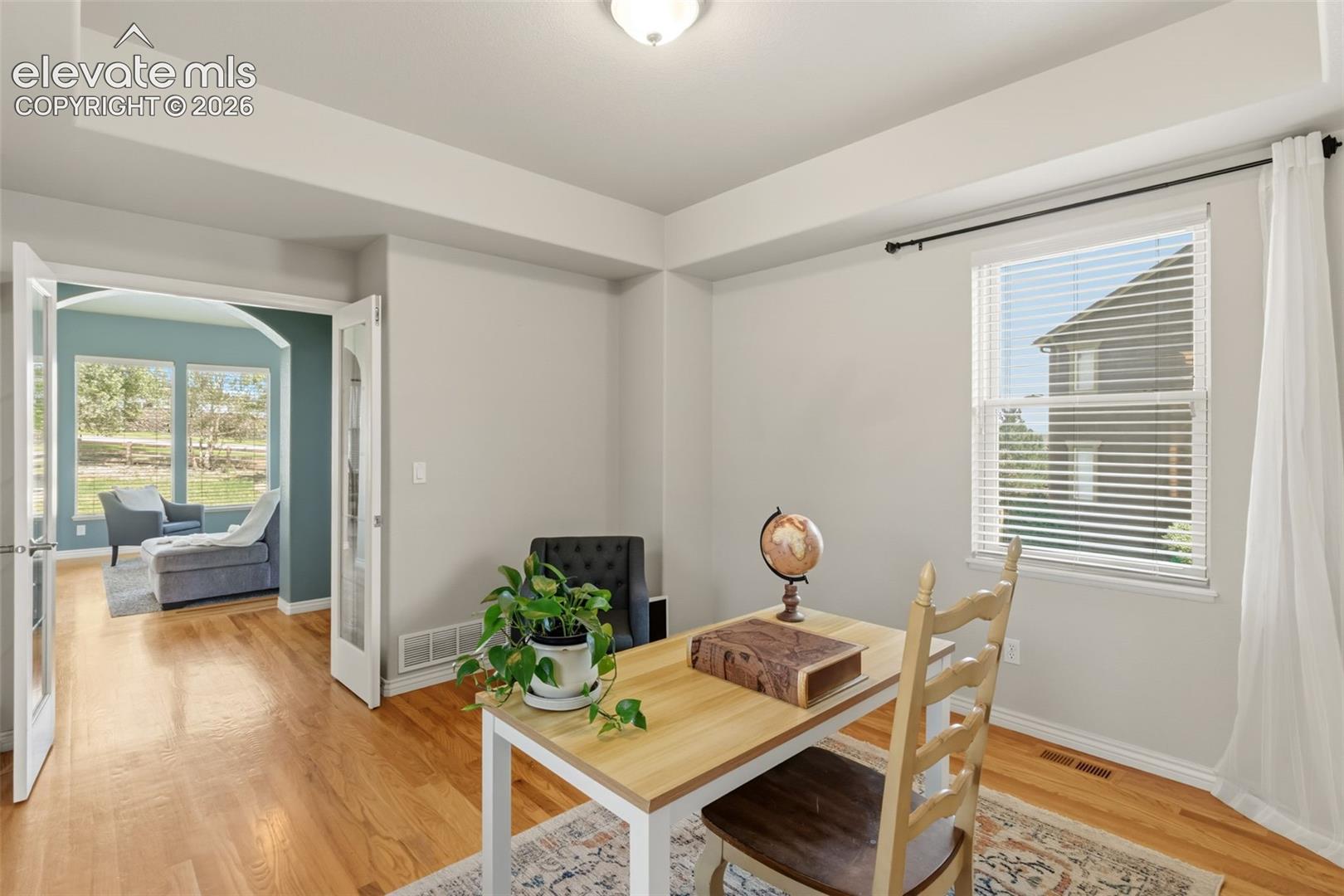 Room with wood-finish flooring, white walls, glass french doors and a recessed ceiling element