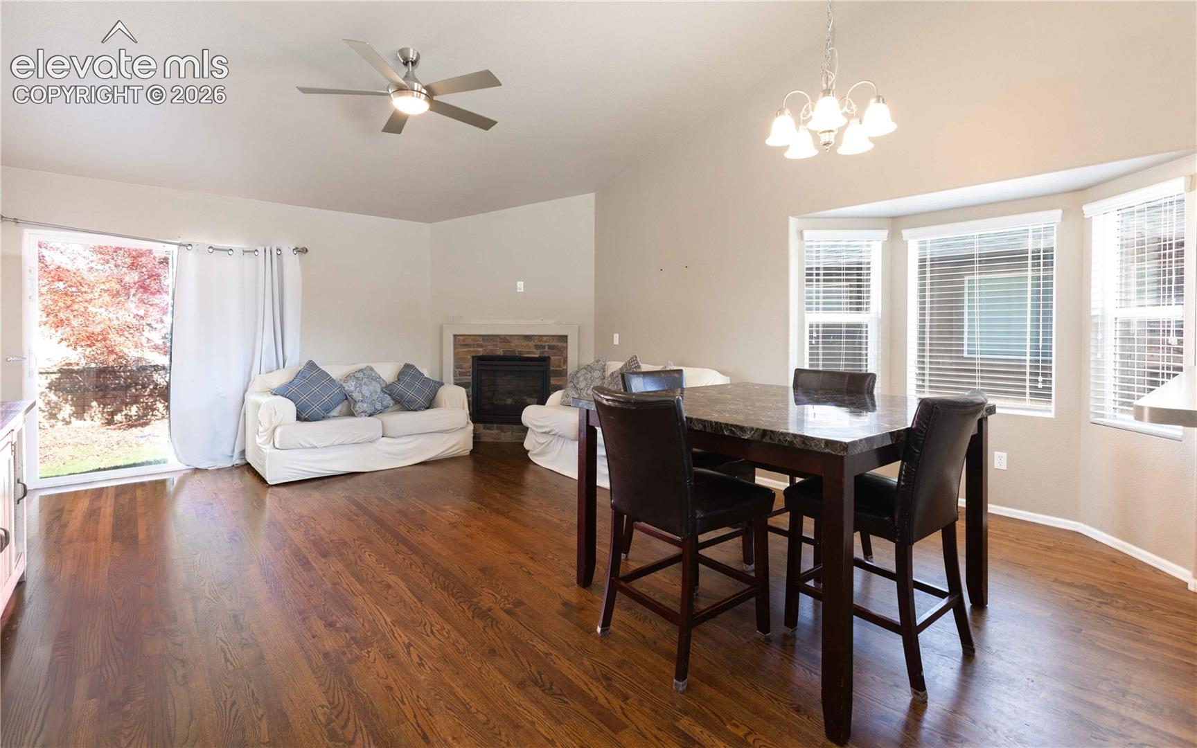 Vaulted ceilings, wood-finish flooring, stone-surround fireplace, bay windows, and sliding glass door