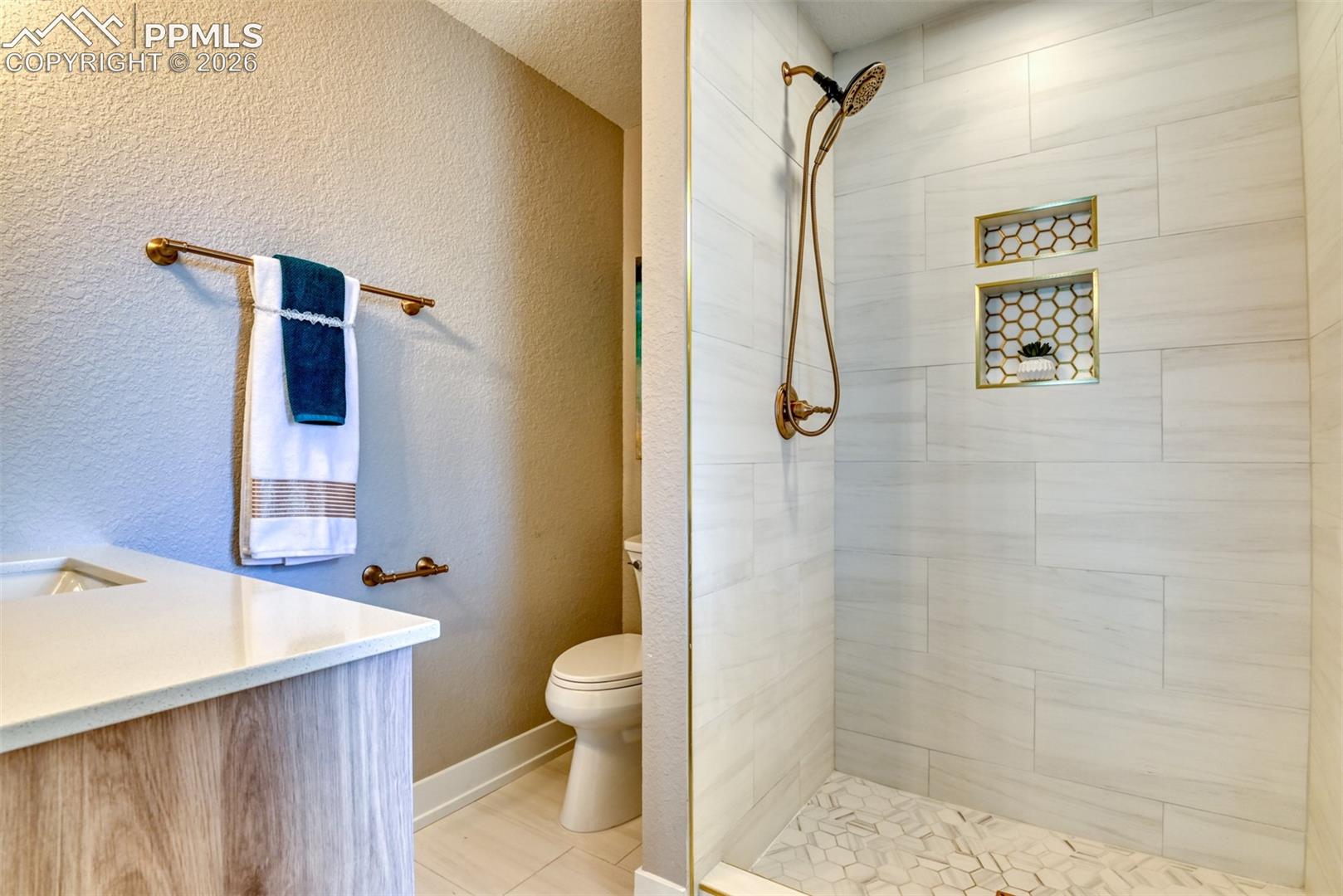 Full bathroom with a textured wall, vanity, and a tile shower
