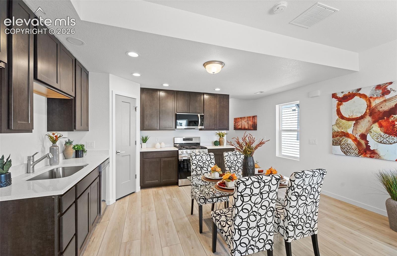 Kitchen featuring dark wood-finish cabinetry, solid-surface countertops, stainless steel appliances, recessed lighting, and wood-finish flooring