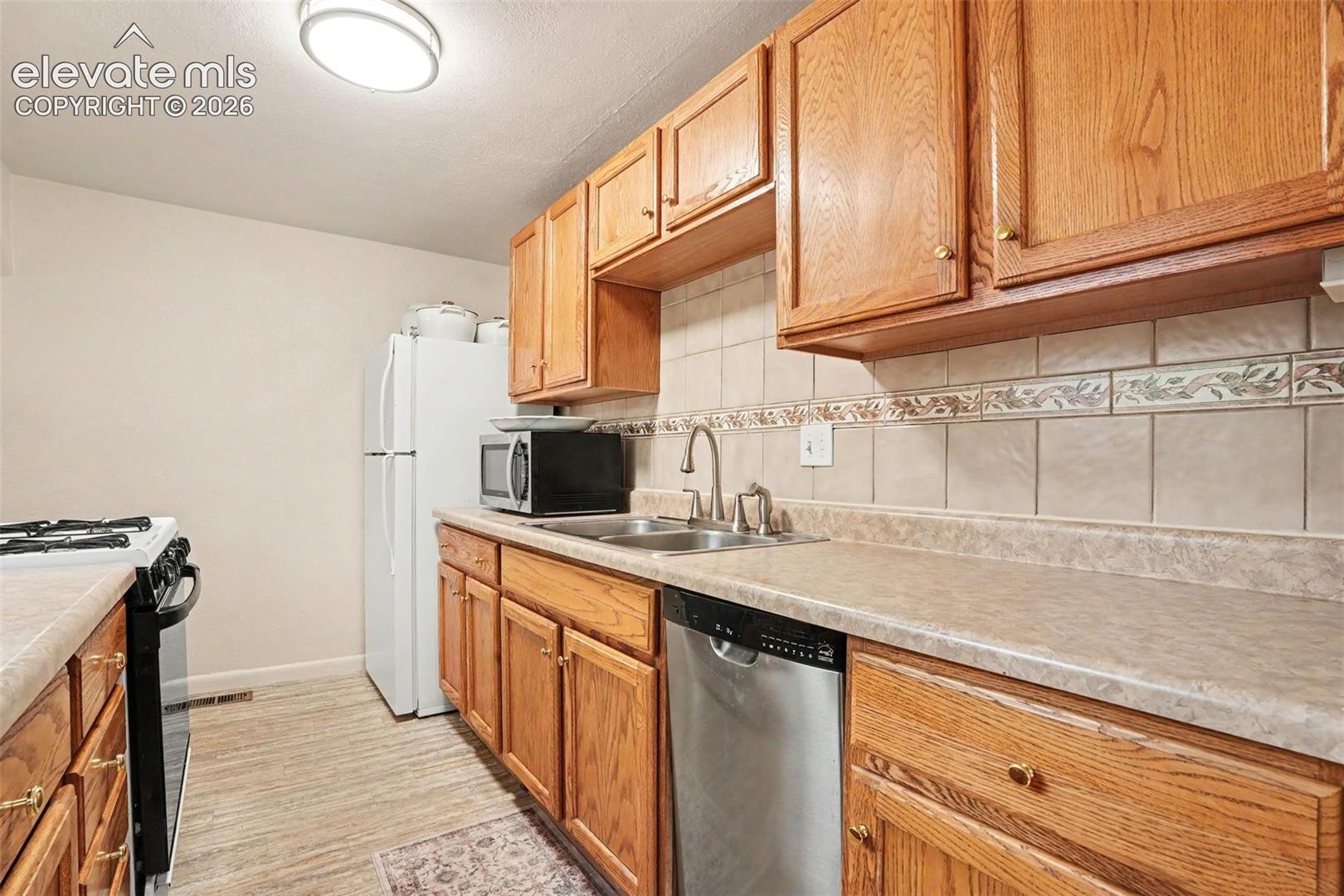 Ceramic tile backsplash, oak cabinetry, and gas stove.