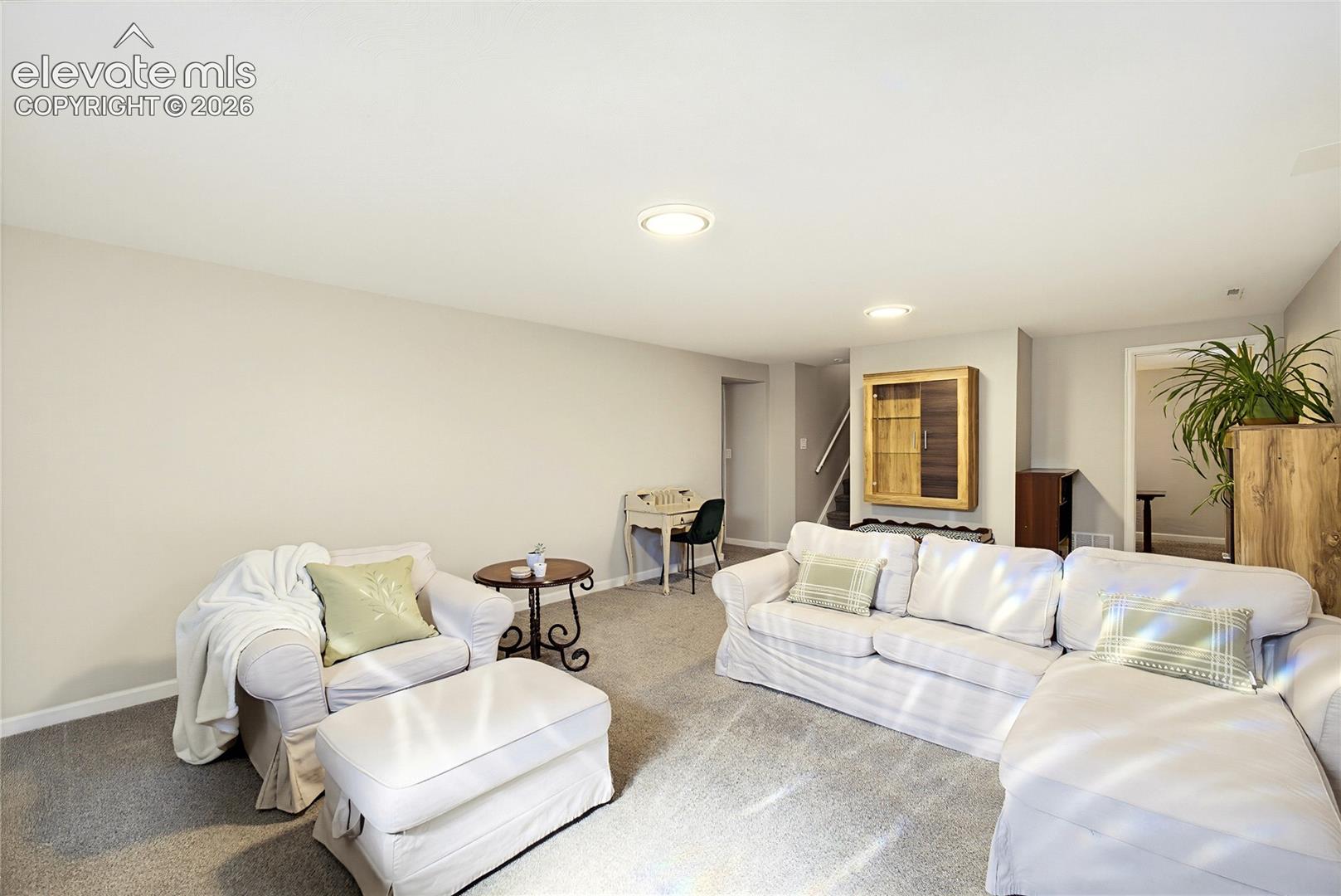 Neutral wall tones, wall-to-wall carpeting, recessed ceiling lighting, and a built-in recessed cabinet with a wood-finish frame