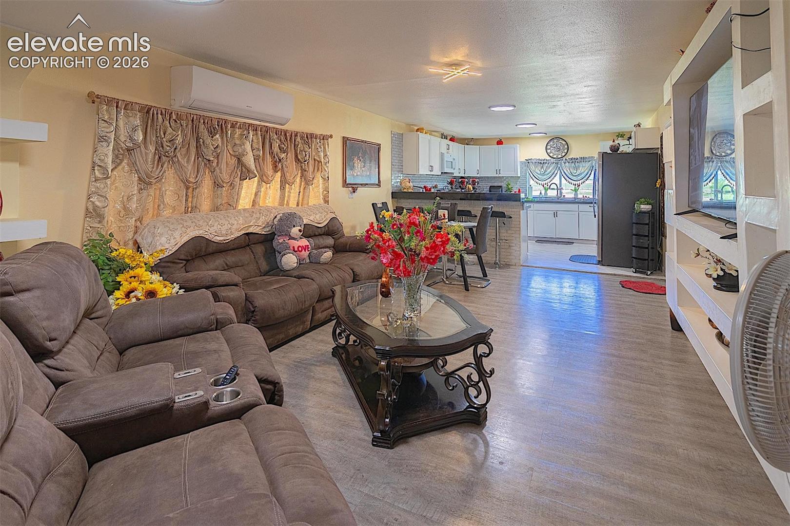 Living room with an AC wall unit and light wood-type flooring