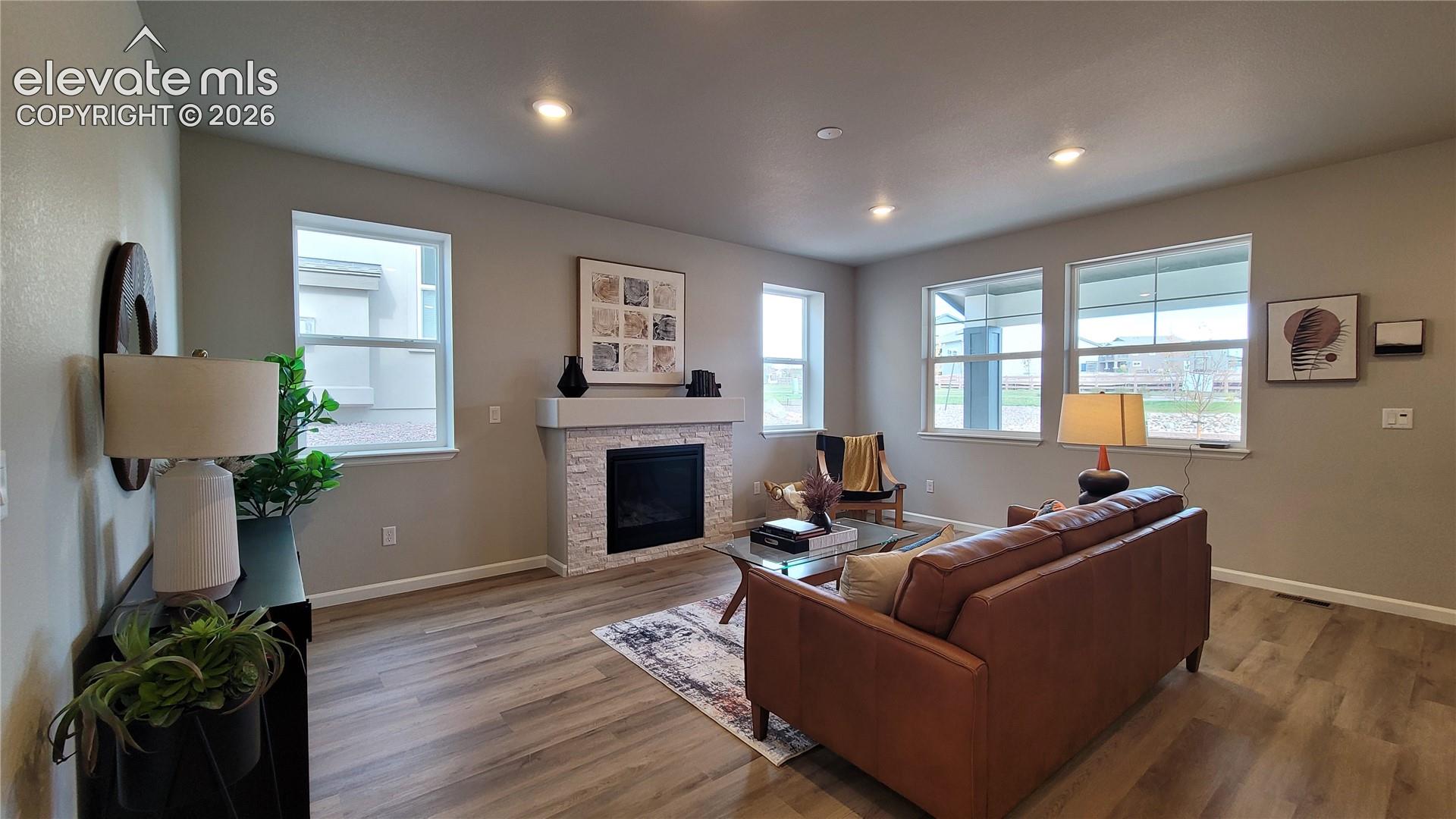 Living area featuring LVP flooring, recessed lighting, and a fireplace with a stacked stone surround!