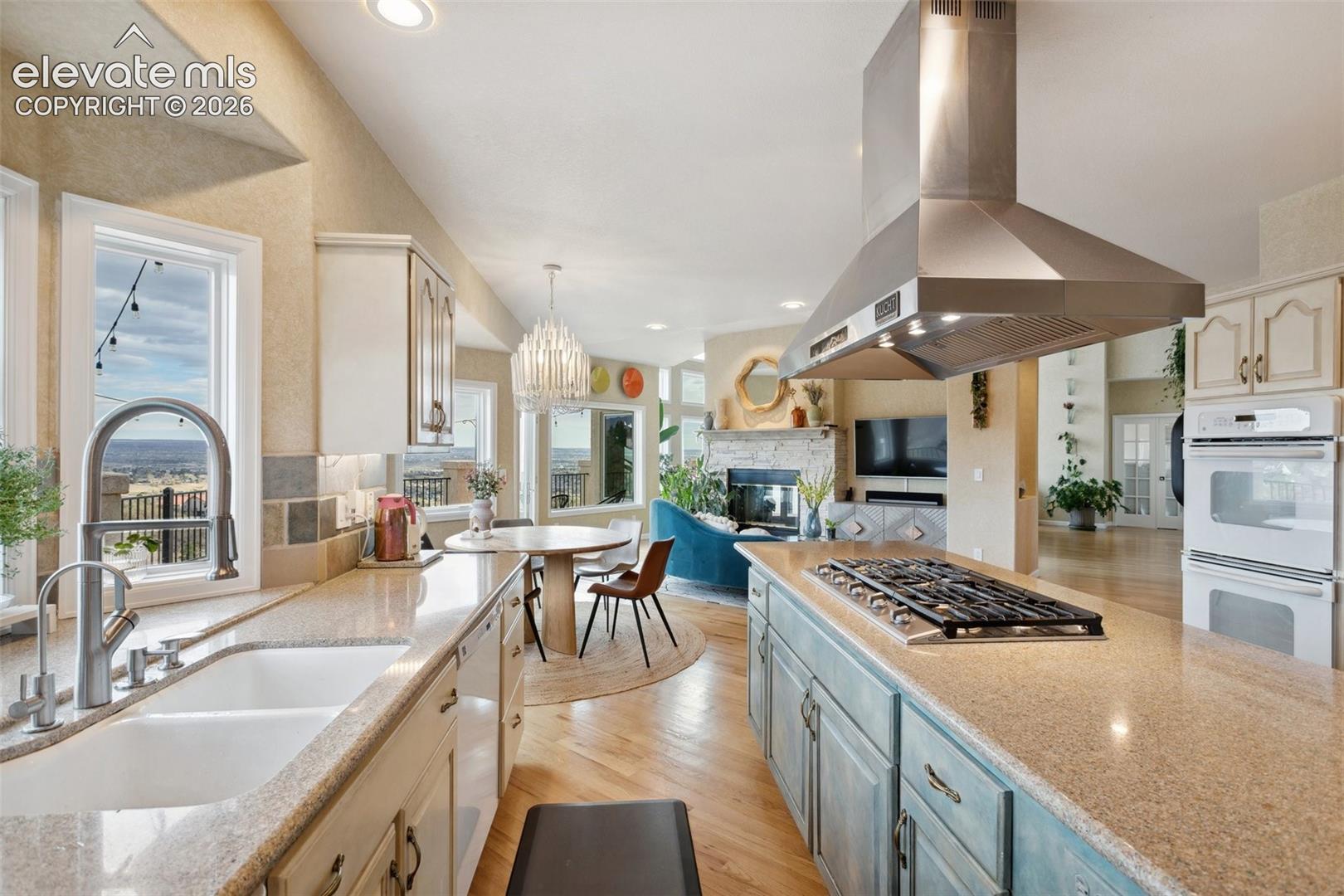 Open-concept kitchen featuring a large island with a built-in gas cooktop and an overhead stainless steel ventilation hood
