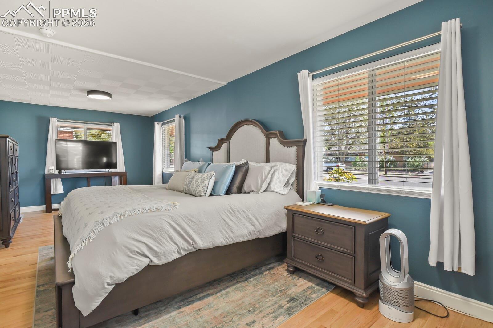 Spacious primary bedroom featuring hardwood flooring and multiple windows
