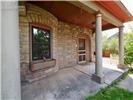 Covered front porch featuring a stone veneer facade, decorative brick arch detailing, concrete flooring, and structural columns
