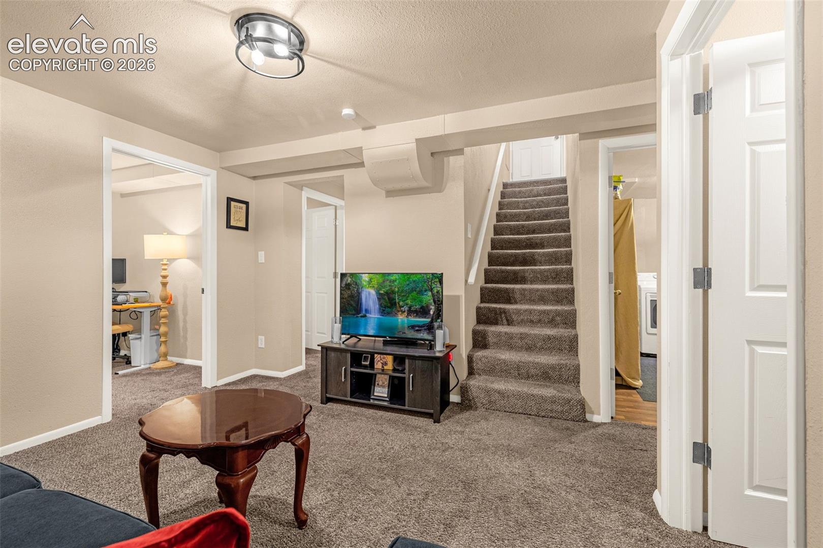 Carpeted family room with a staircase to the main level, and access to additional bedroom spaces