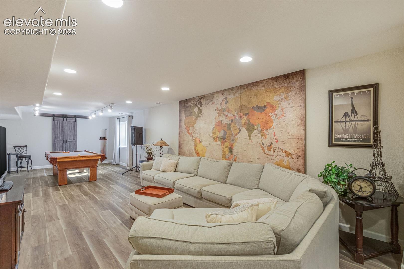 Open-concept interior featuring wood-finish flooring, recessed lighting, and a barn-style sliding door