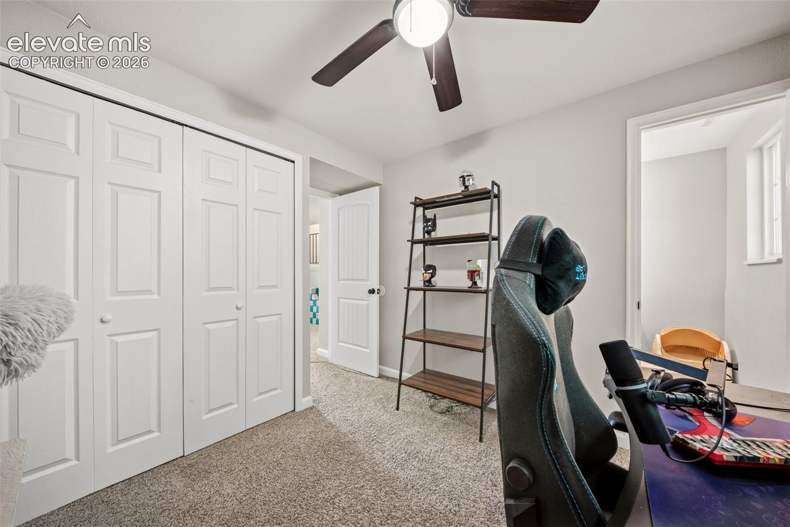 Carpeted flooring, bi-fold closet doors, ceiling fan with integrated lighting, and a white interior door with dark hardware