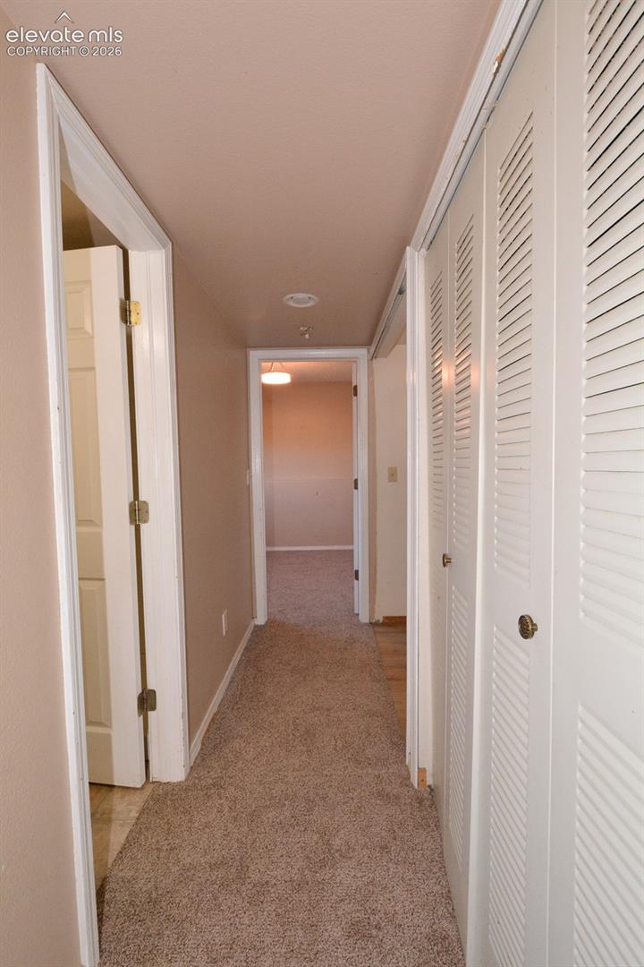 Hallway with carpet flooring, recessed lighting, white louvered bifold doors, and painted walls