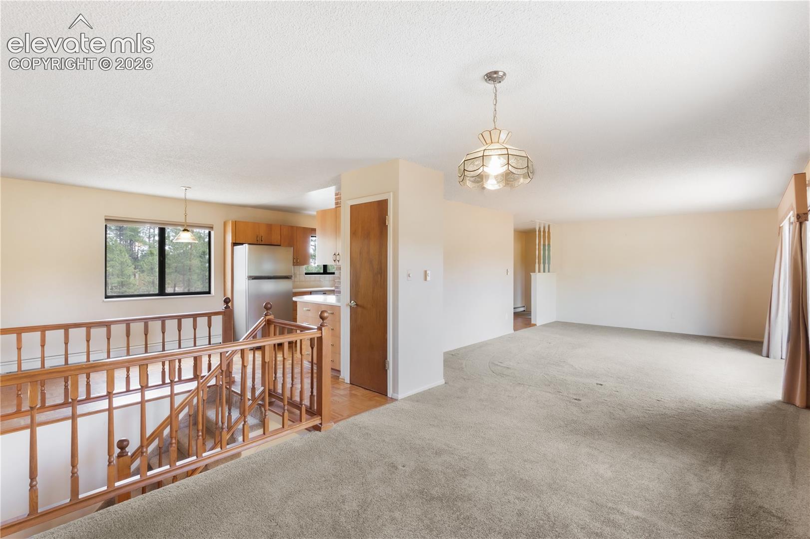 Dining area and living room looking toward the kitchen, stairs to basement to the left