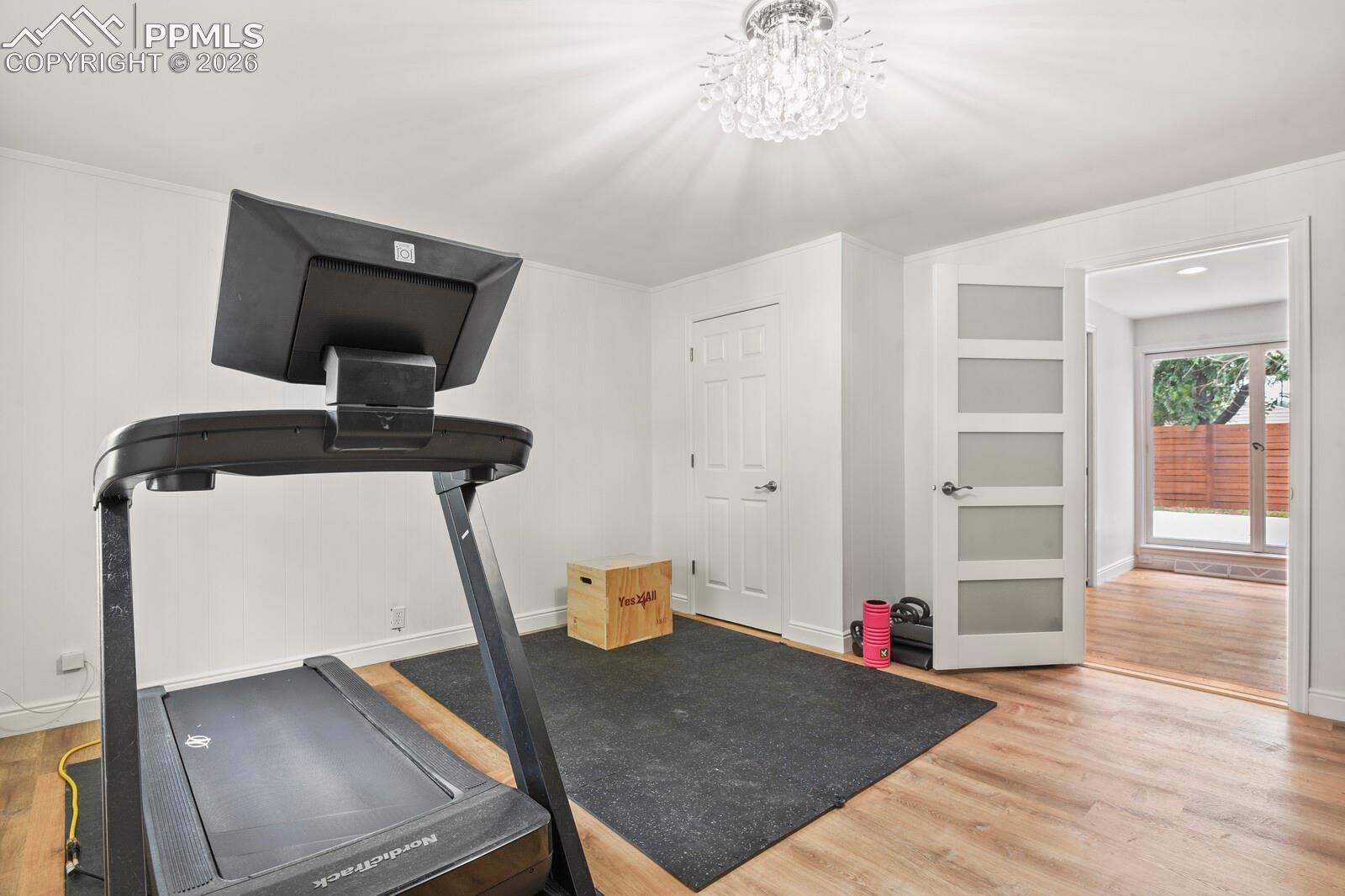 3rd bedroom on main level. Modern interior door with opaque glass panels, hardwood flooring and a chandelier