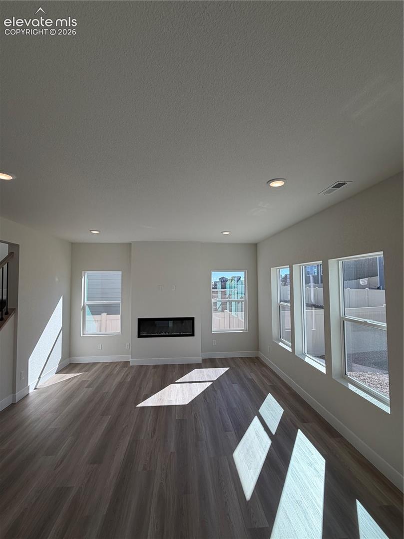Interior space featuring wood-finish flooring, a built-in electric fireplace, recessed ceiling lighting, and multiple windows