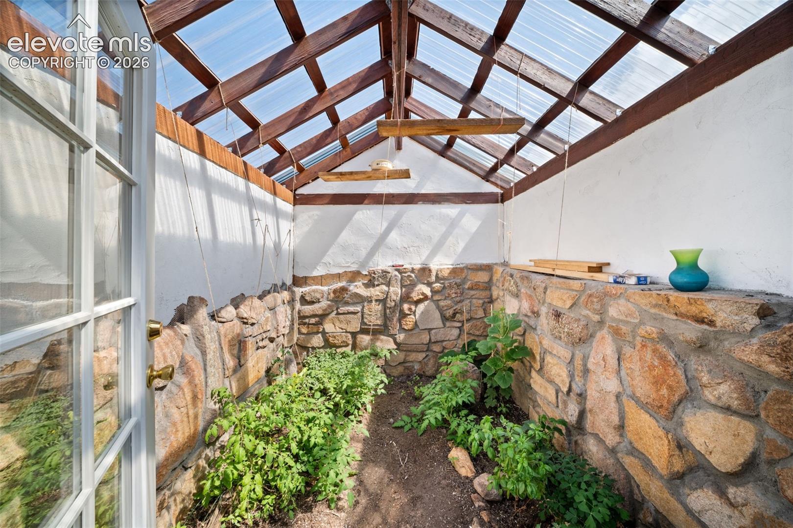 Custom-built greenhouse with attractive stone accents.