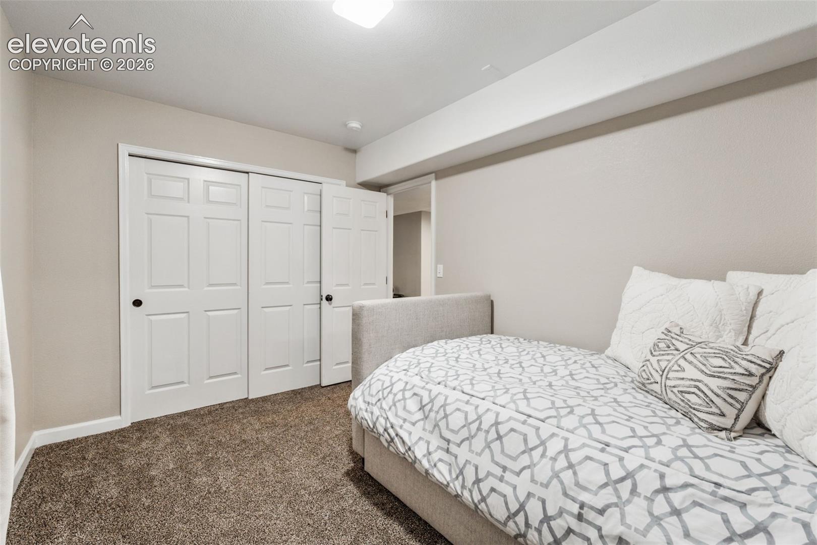 Neutral interior featuring plush carpeting, crisp wall paint, and multi-panel closet doors with hardware